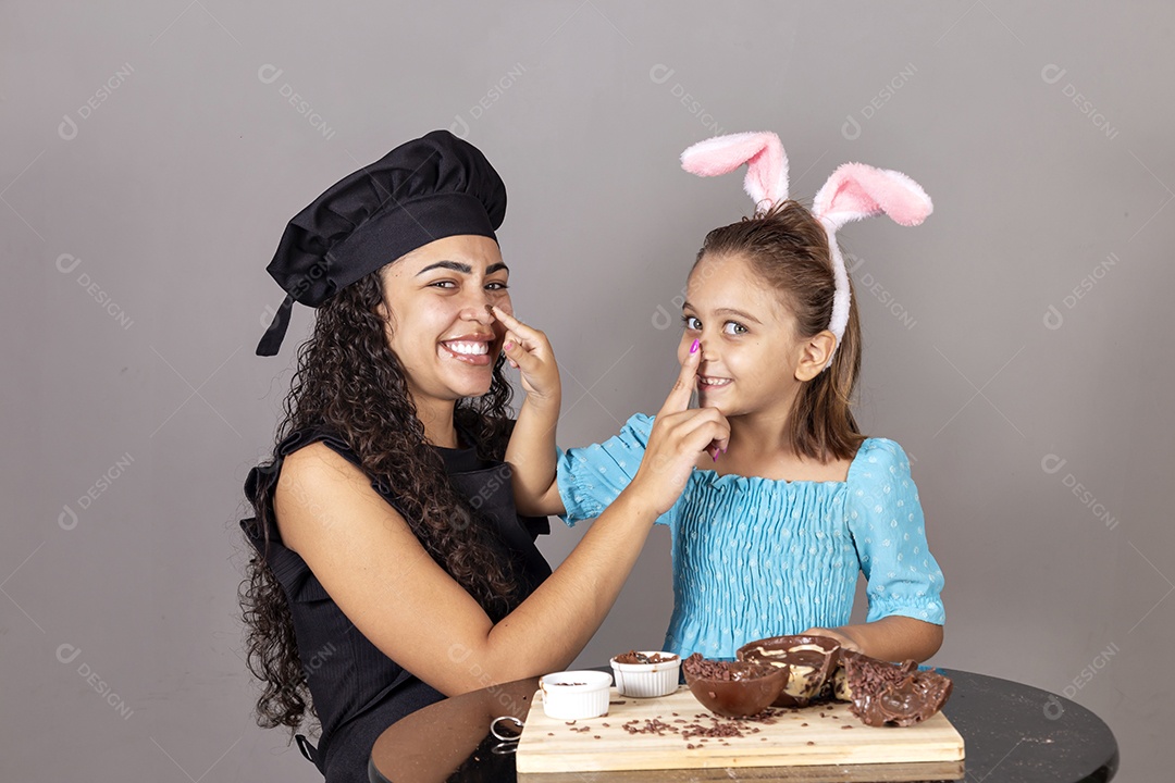 Mãe ao lado de sua filha comendo ovos de páscoa