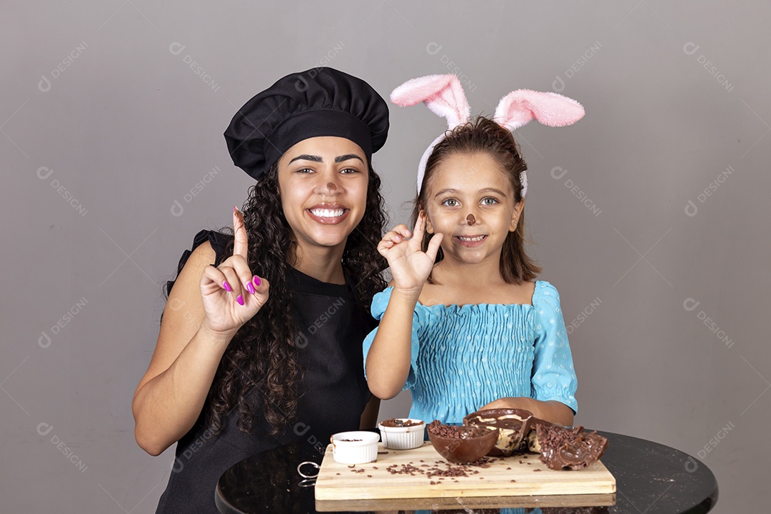 Mãe ao lado de sua filha comendo ovos de páscoa