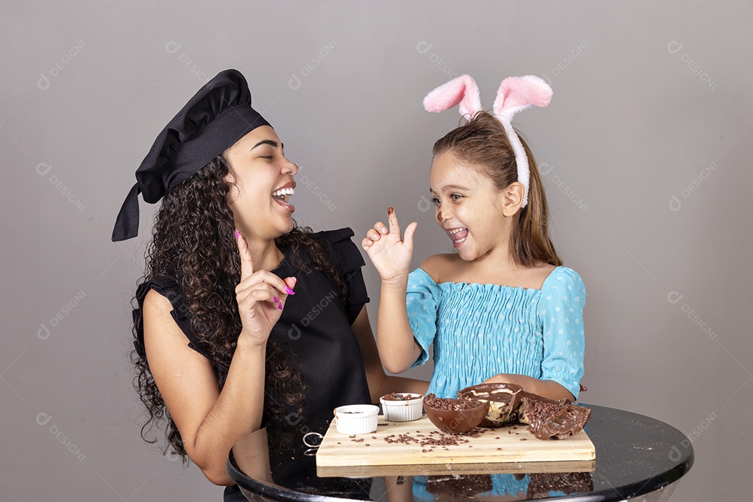 Mãe ao lado de sua filha comendo ovos de páscoa