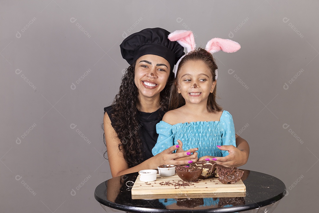 Mãe ao lado de sua filha comendo ovos de páscoa