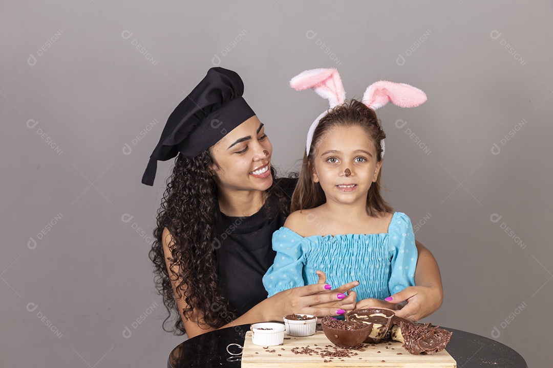 Mãe ao lado de sua filha comendo ovos de páscoa