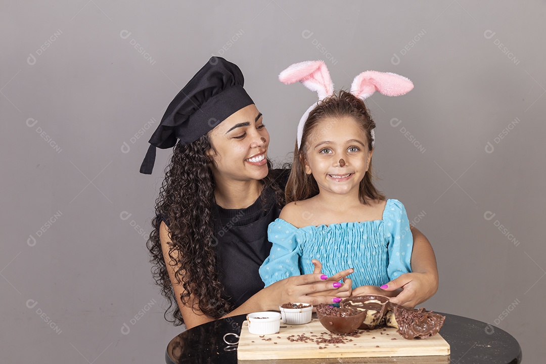 Mãe ao lado de sua filha comendo ovos de páscoa