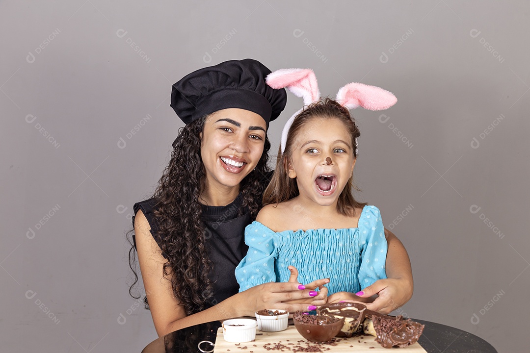 Mãe ao lado de sua filha comendo ovos de páscoa