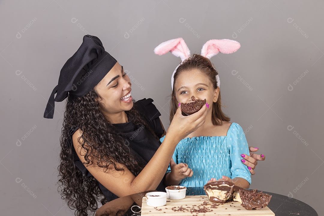 Mãe ao lado de sua filha comendo ovos de páscoa