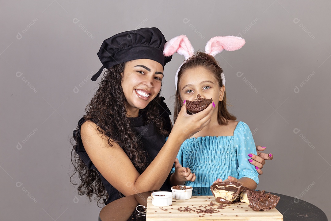 Mãe ao lado de sua filha comendo ovos de páscoa