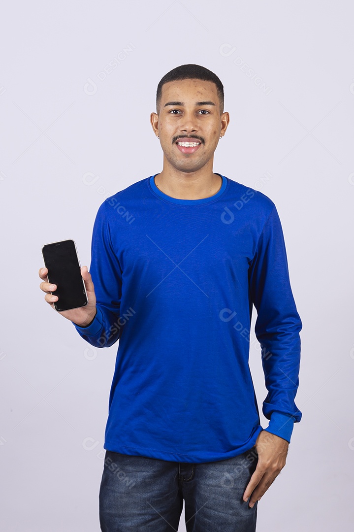 Homem jovem sorridente usando camiseta azul segurando celular smartphone