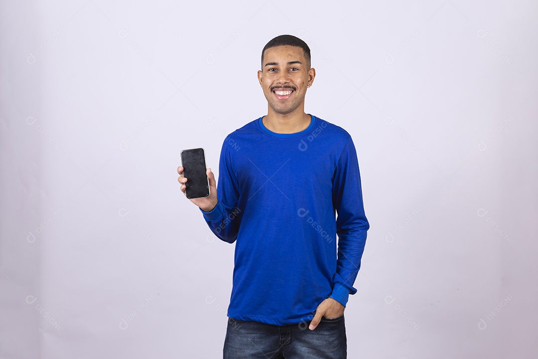 Homem jovem sorridente usando camiseta azul segurando celular smartphone