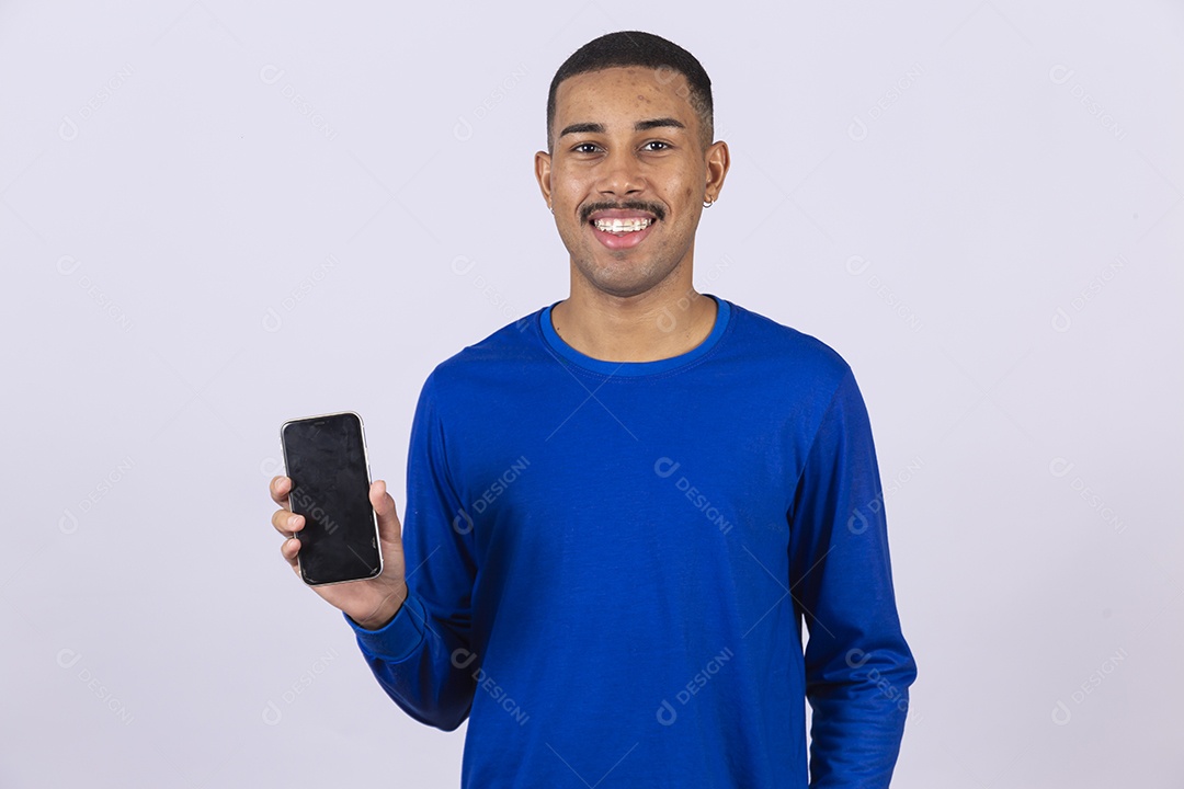 Homem jovem sorridente usando camiseta azul segurando celular smartphone