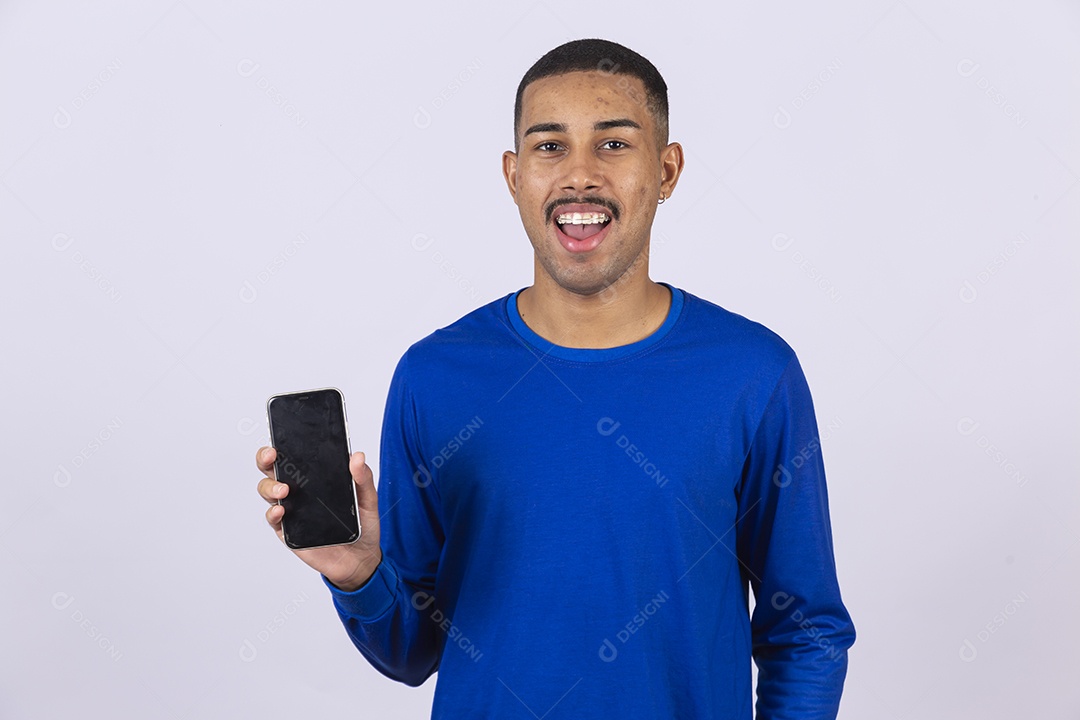 Homem jovem sorridente usando camiseta azul segurando celular smartphone