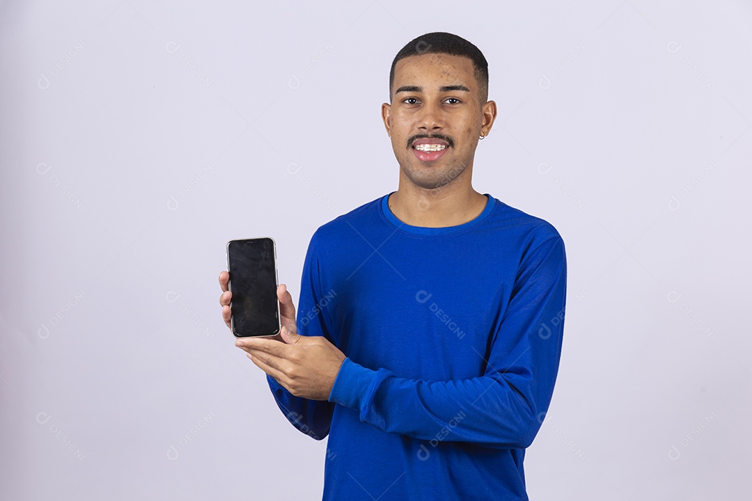 Homem jovem sorridente usando camiseta azul segurando celular smartphone