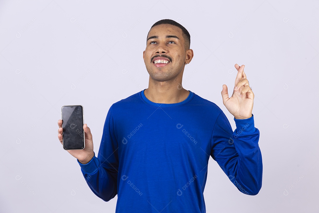 Homem jovem sorridente usando camiseta azul segurando celular smartphone