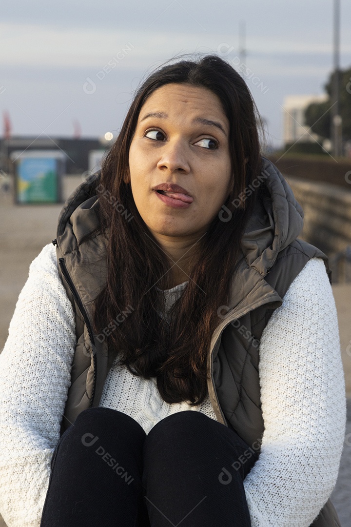 Uma jovem mulher fazendo poses para foto sentada em uma banco
