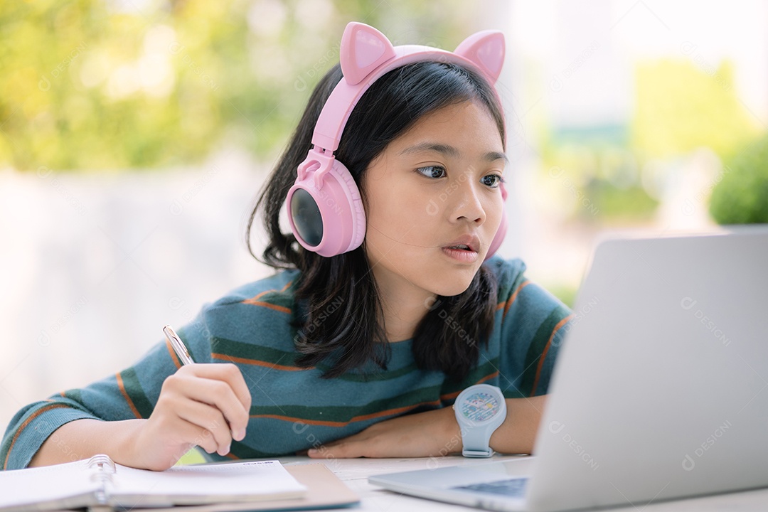 Garotinha estudando em seu laptop com fones de ouvido rosa