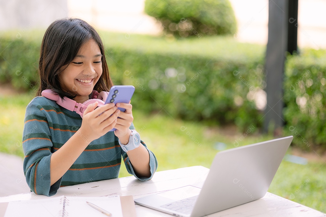 Garota usando notebook e mexendo no celular
