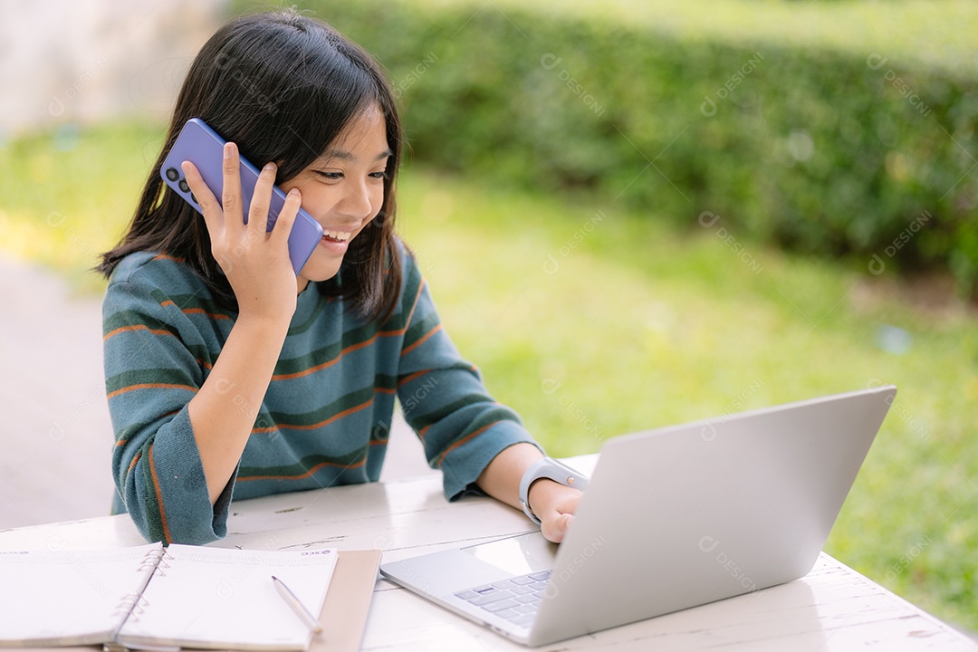 Uma garotinha usando notebook e falando ao telefone