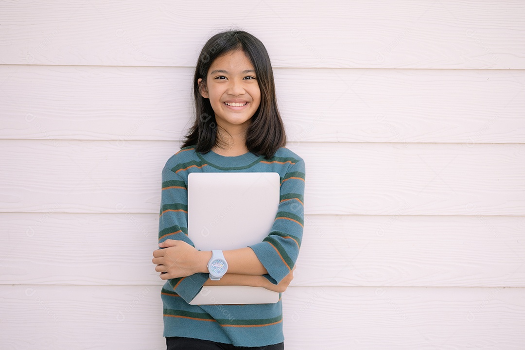 Uma criança está segurando um laptop nos braços e sorrindo