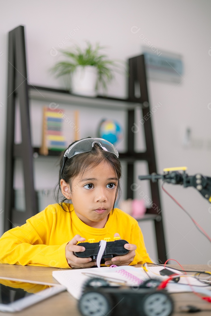 Uma criança de camisa amarela está brincando com um carro de controle remoto