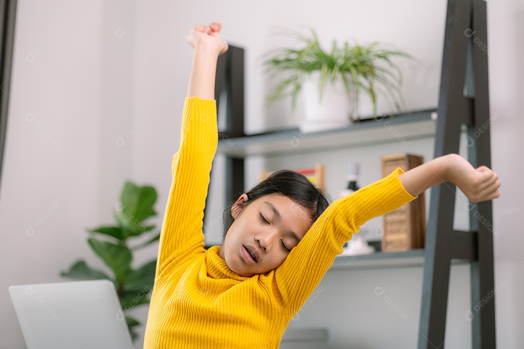 Garotinha está esticando os braços com preguiça na frente do laptop