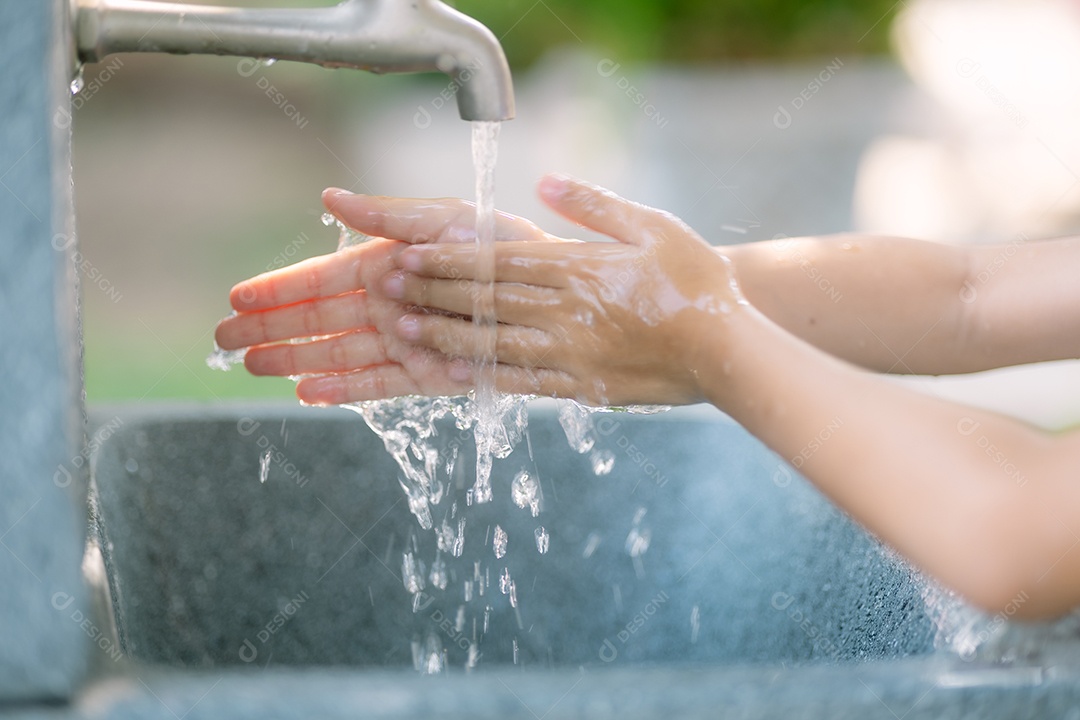 Mãos de crianças lavando as mãos na torneira com água