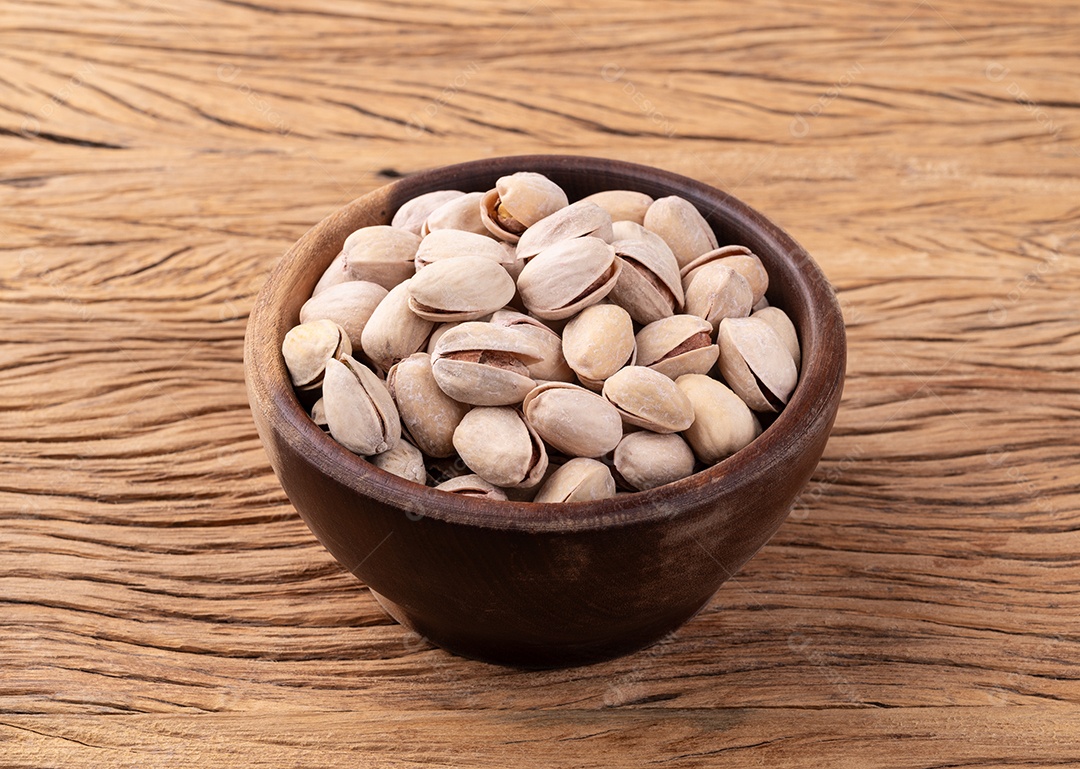 Pistácios torrados salgados em uma tigela sobre a mesa de madeira