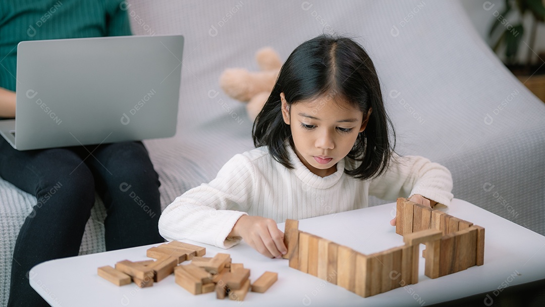 Uma menina linda está brincando com blocos de madeira sobre uma mesa