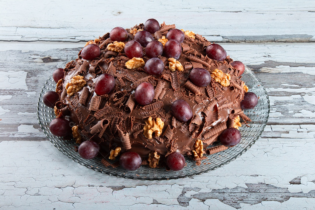 Bolo com cobertura de chocolate e uvas sobre uma bandeja de vidro