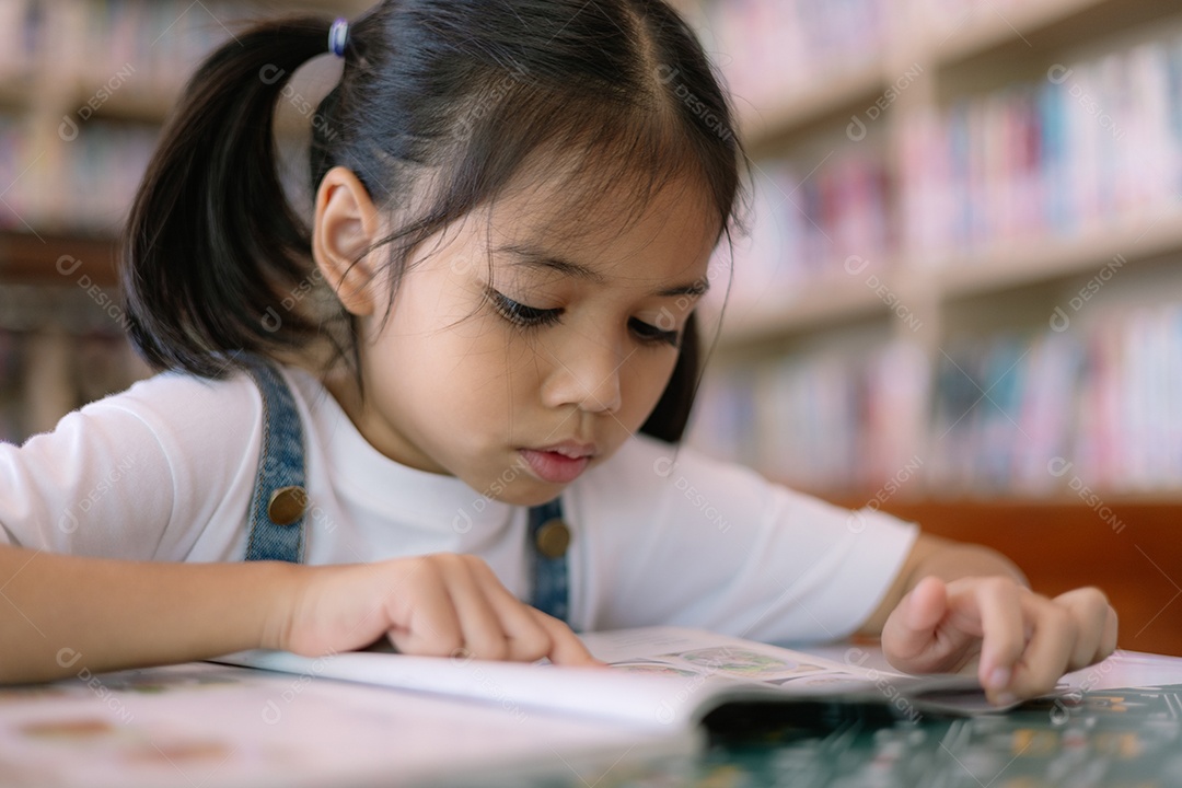 Bela menina lendo livros em biblioteca
