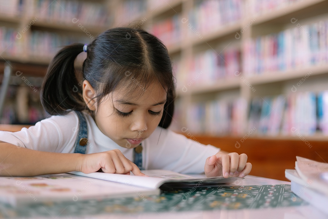 Bela menina lendo livros em biblioteca
