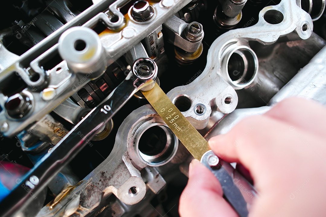 Mecânico verificando e ajustando válvulas do motor do carro com medidor