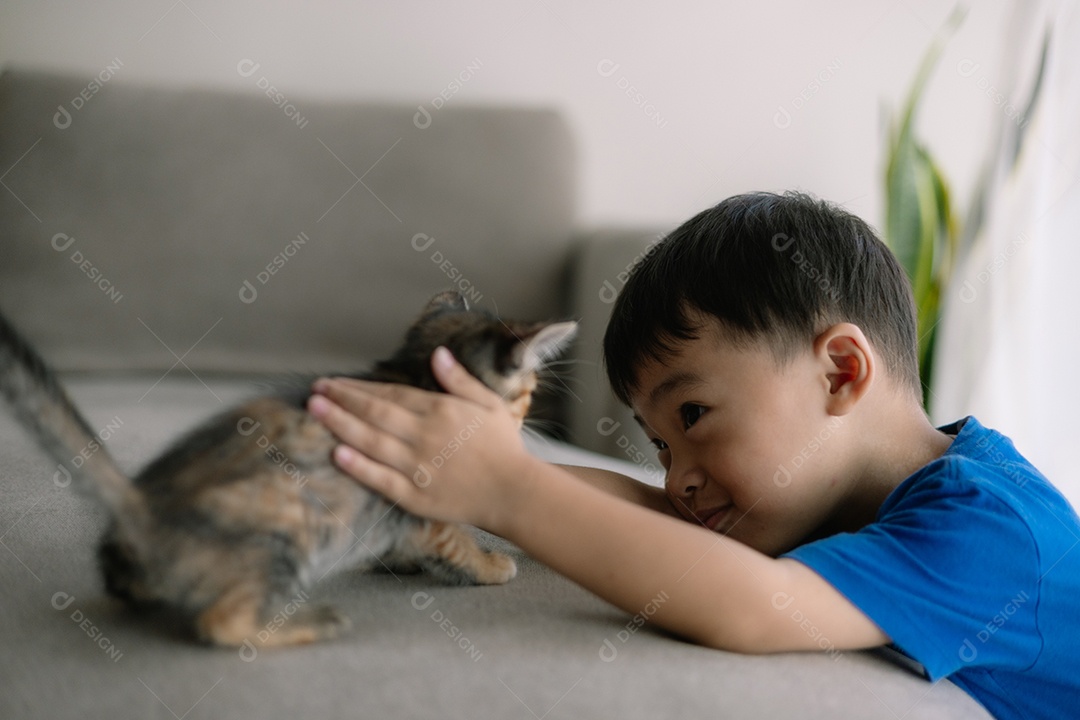 Um menino fofo brincando com seu gatinho