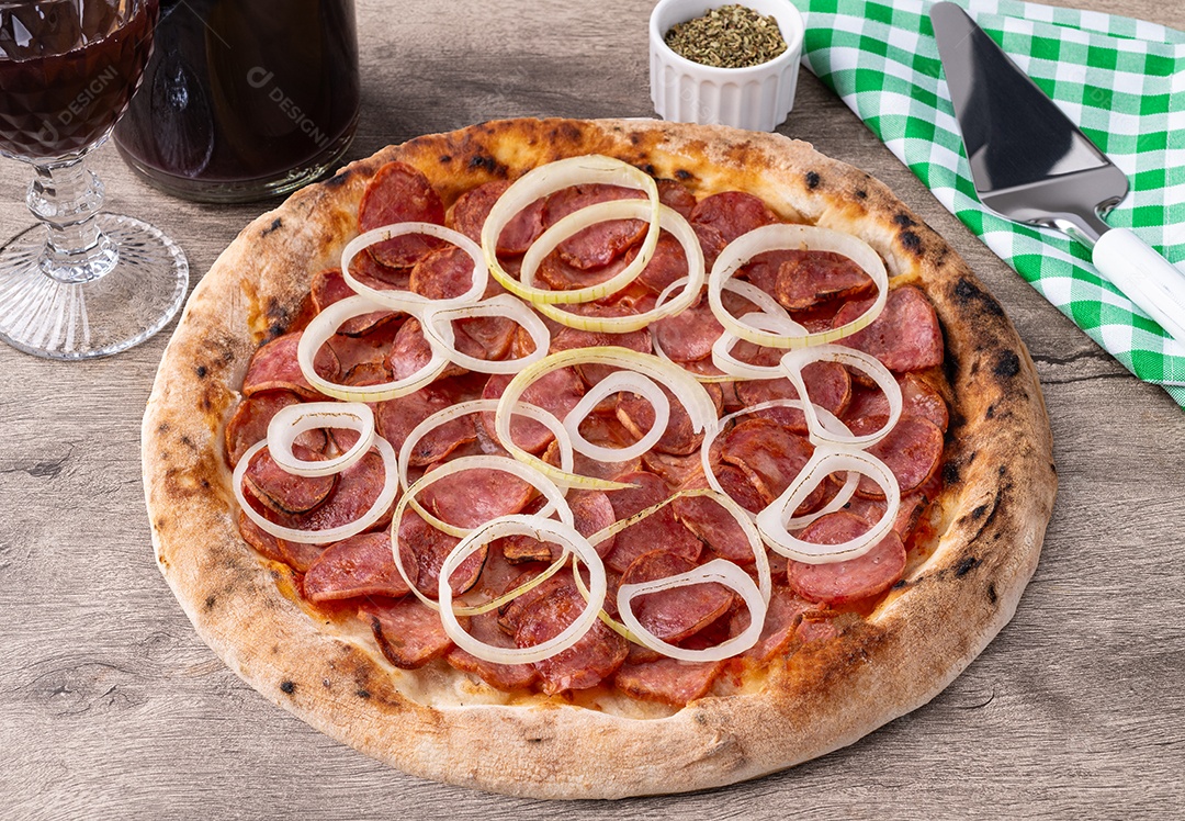 Pizza calabresa acebolada acompanhada de vinho sobre a mesa