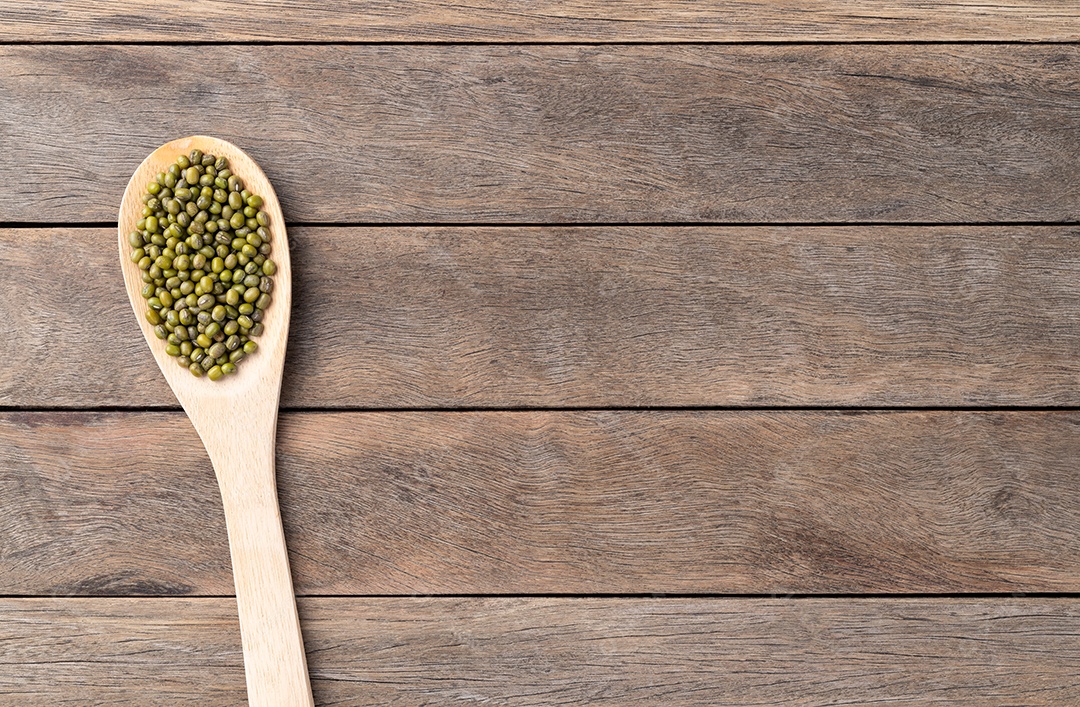 Colher de madeira com grão de feijão verde fundo de madeira