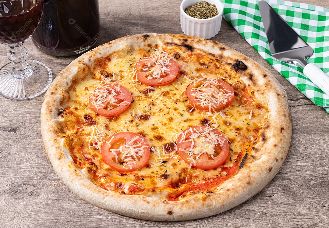 Pizza napolitana com taça cheia de vinho e garrafa encima da mesa de madeira