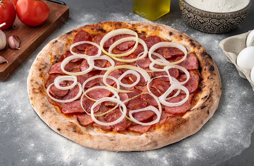 Pizza de calabresa com cebola tomate sobre fundo de pedra
