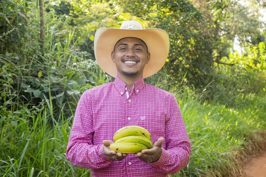 Homem jovem fazendeiro sobre fazenda segurando banana