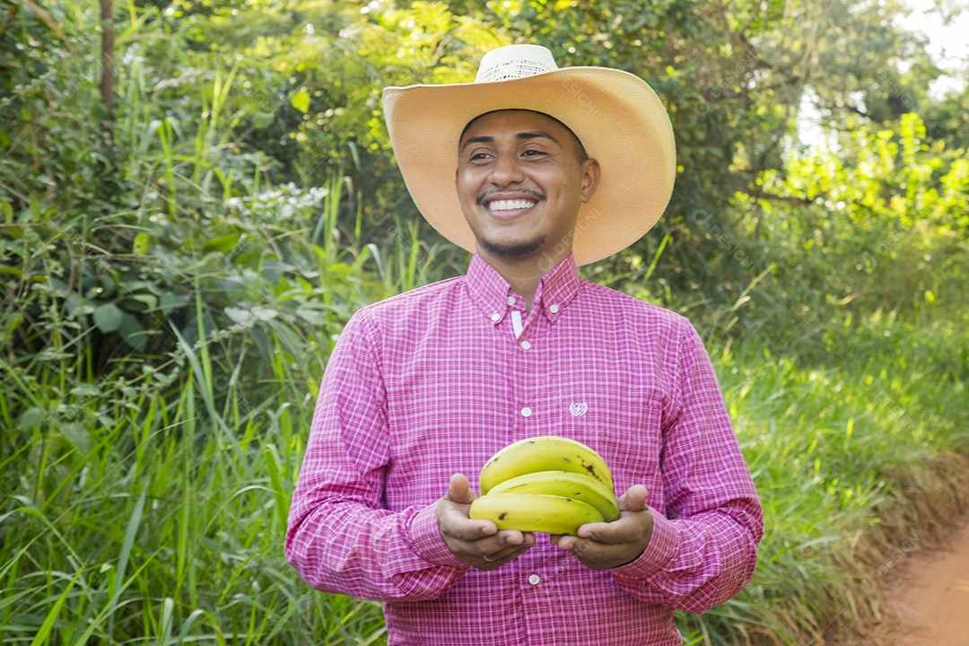 Homem jovem fazendeiro sobre fazenda segurando banana