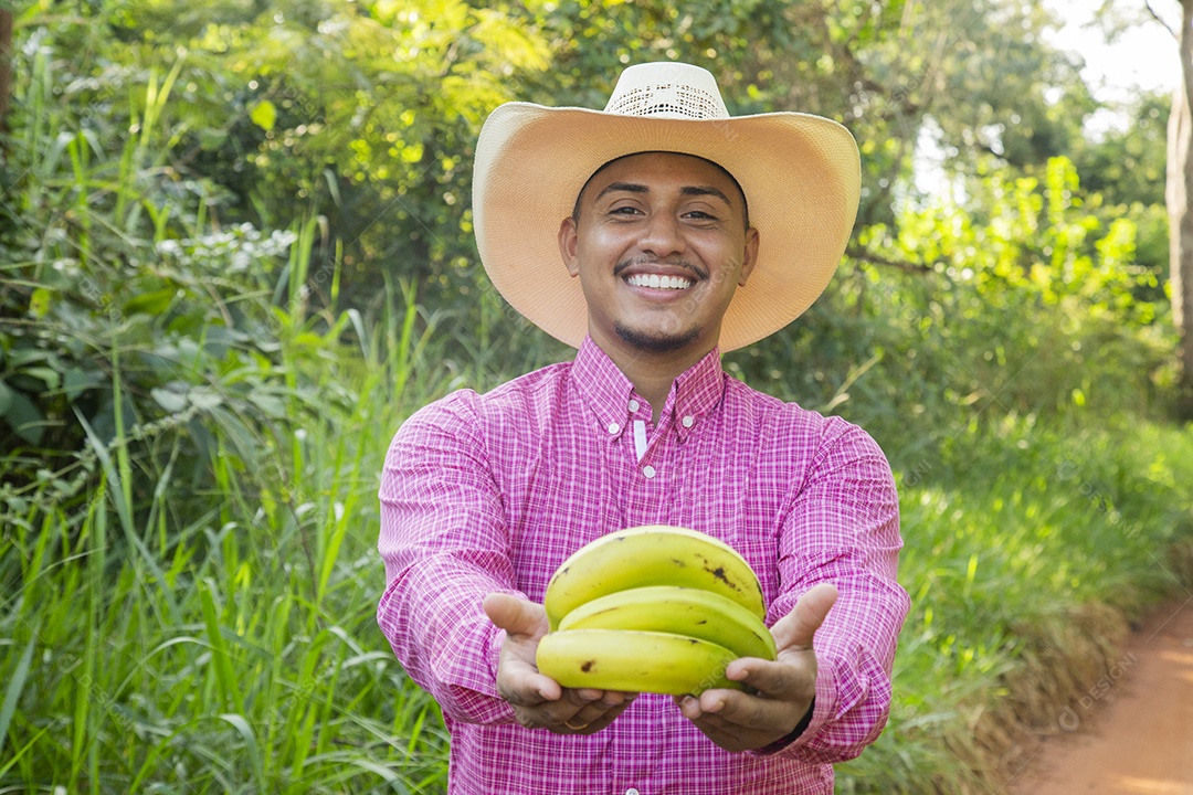 Homem jovem fazendeiro sobre fazenda segurando banana