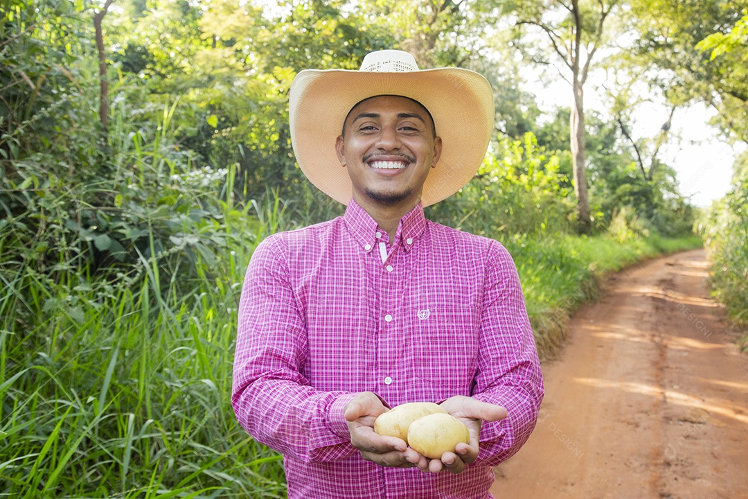 Homem jovem fazendeiro sobre fazenda segurando batatas
