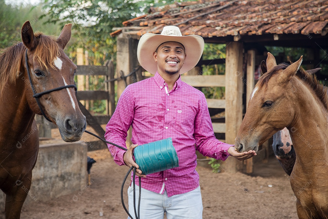 Homem jovem fazendeiro cuidando de seus cavalos