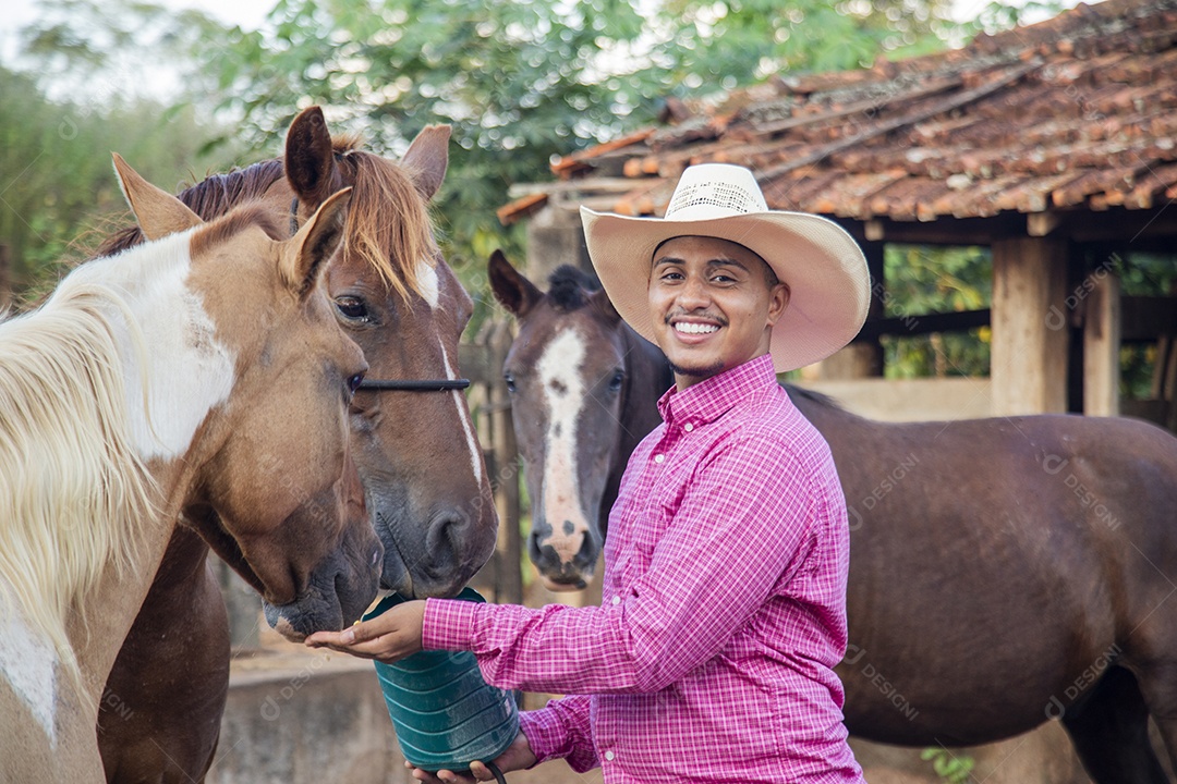 Homem jovem fazendeiro cuidando de seus cavalos