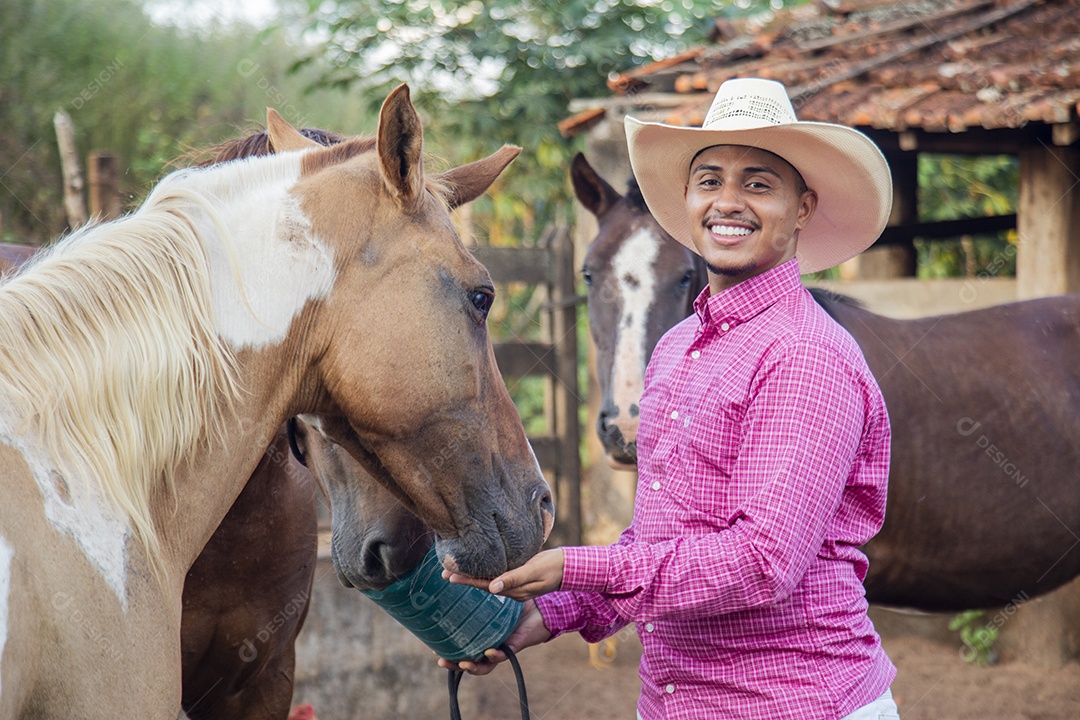 Homem jovem fazendeiro cuidando de seus cavalos