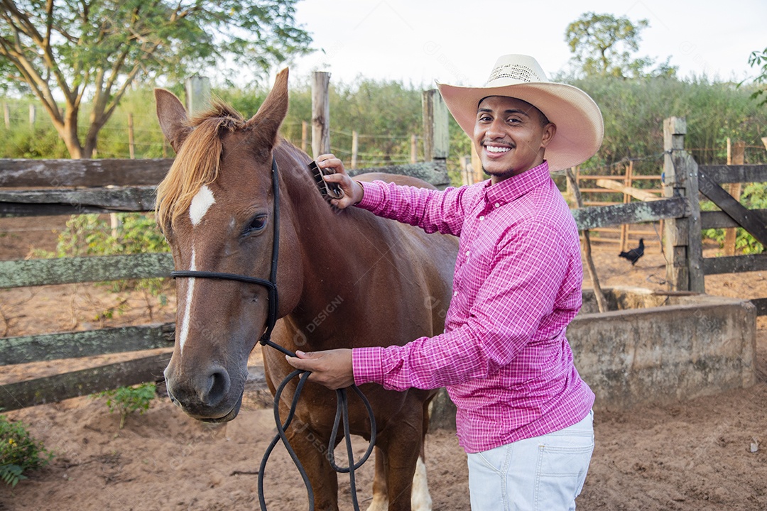 Homem jovem fazendeiro cuidando de seus cavalos