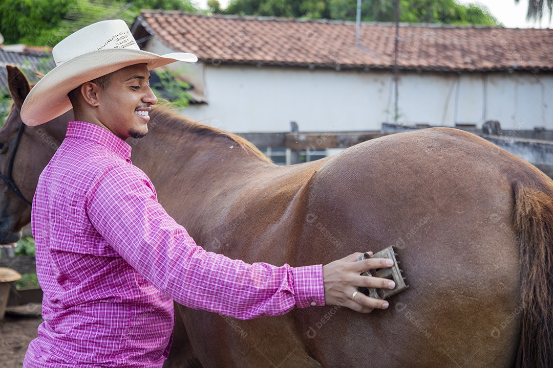 Homem jovem fazendeiro cuidando de seus cavalos