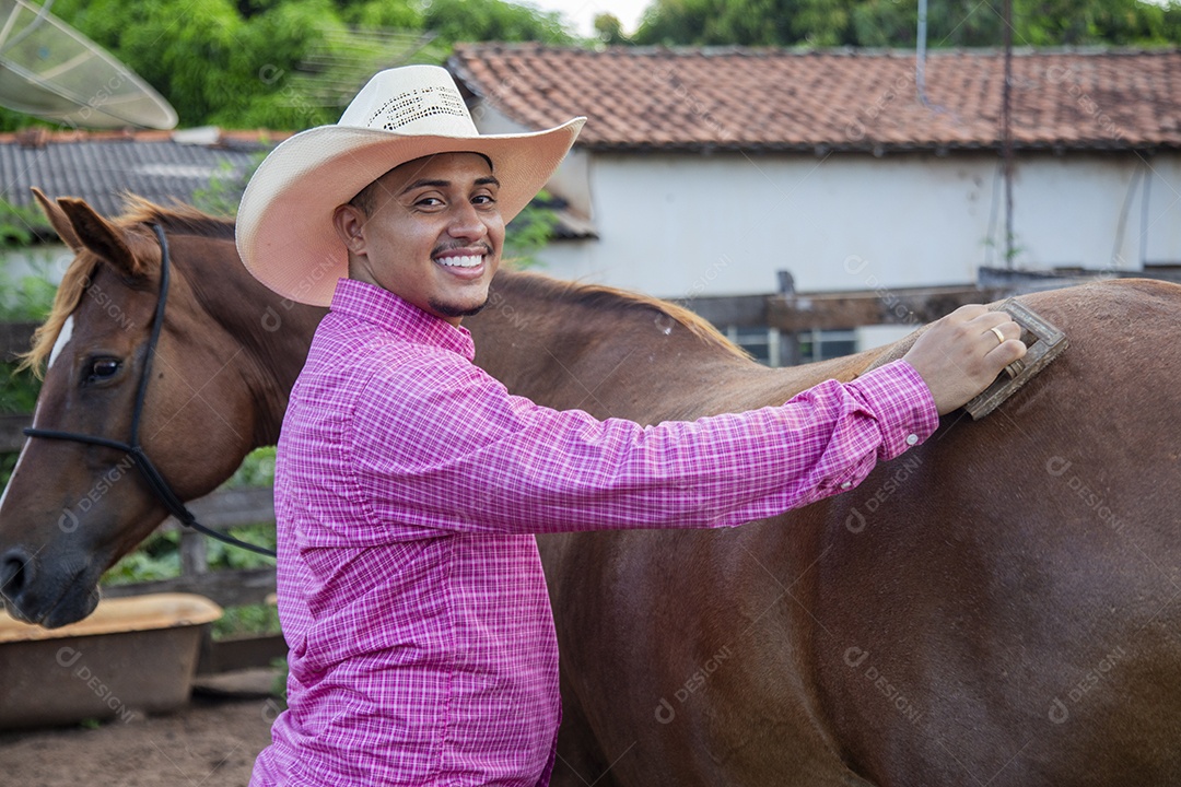 Homem jovem fazendeiro cuidando de seus cavalos