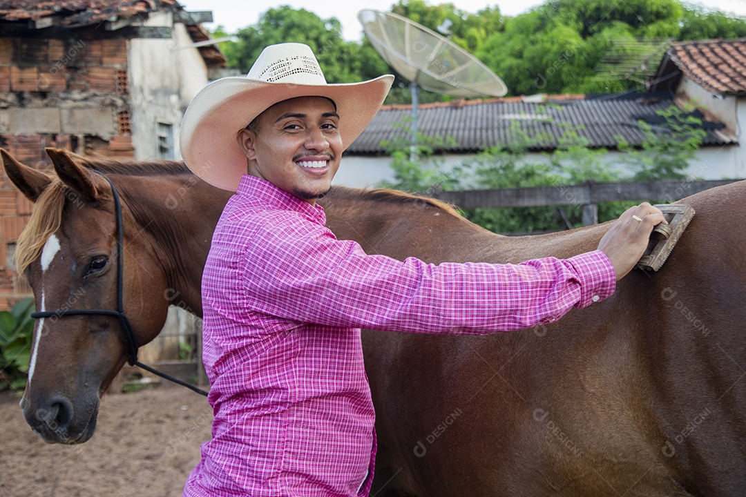 Homem jovem fazendeiro cuidando de seus cavalos