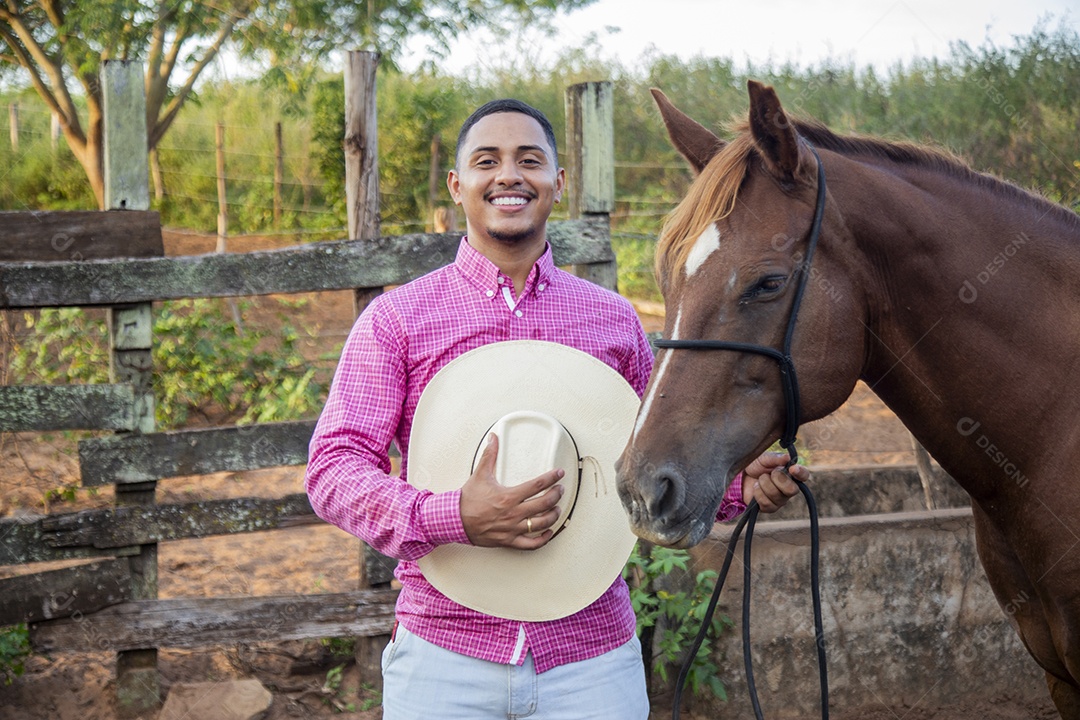 Homem jovem fazendeiro cuidando de seu cavalo
