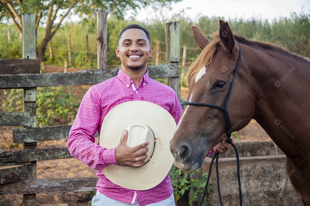 Homem jovem fazendeiro cuidando de seu cavalo