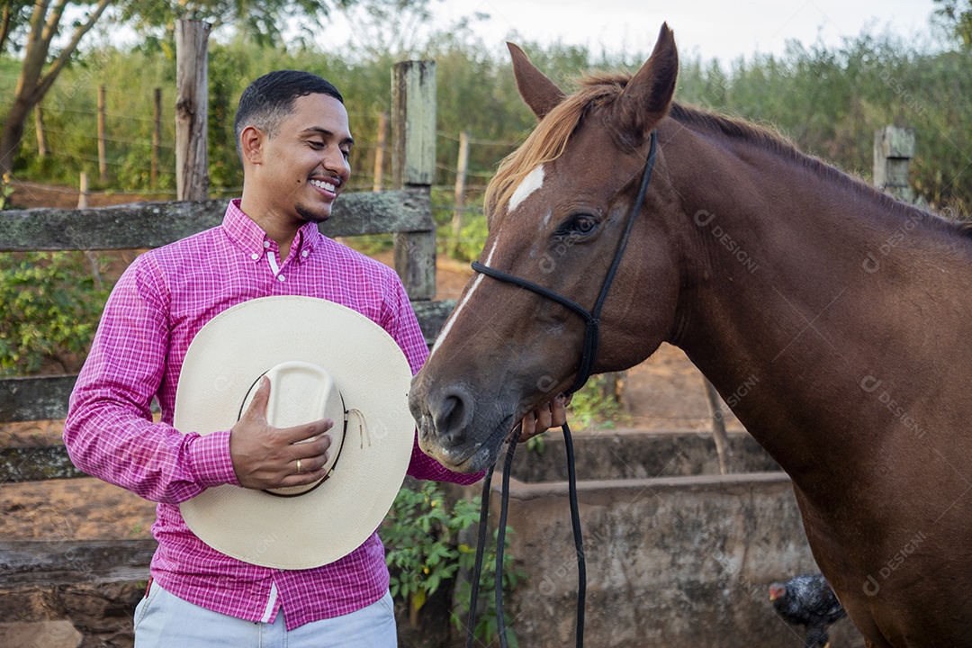 Homem jovem fazendeiro cuidando de seu cavalo