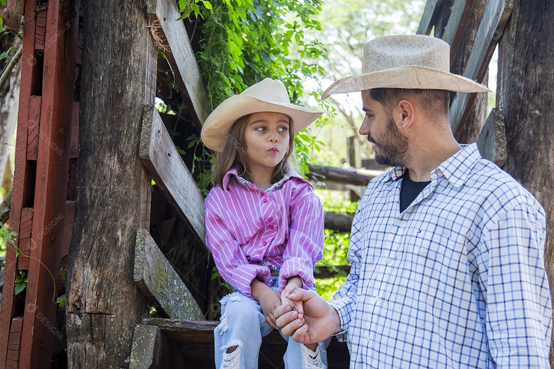 Pai fazendeiro ao lado de sua filha sobre fazenda