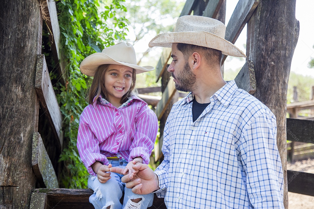 Pai fazendeiro ao lado de sua filha sobre fazenda